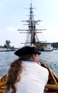 Michael, rowing his boat (towards the tall ship)